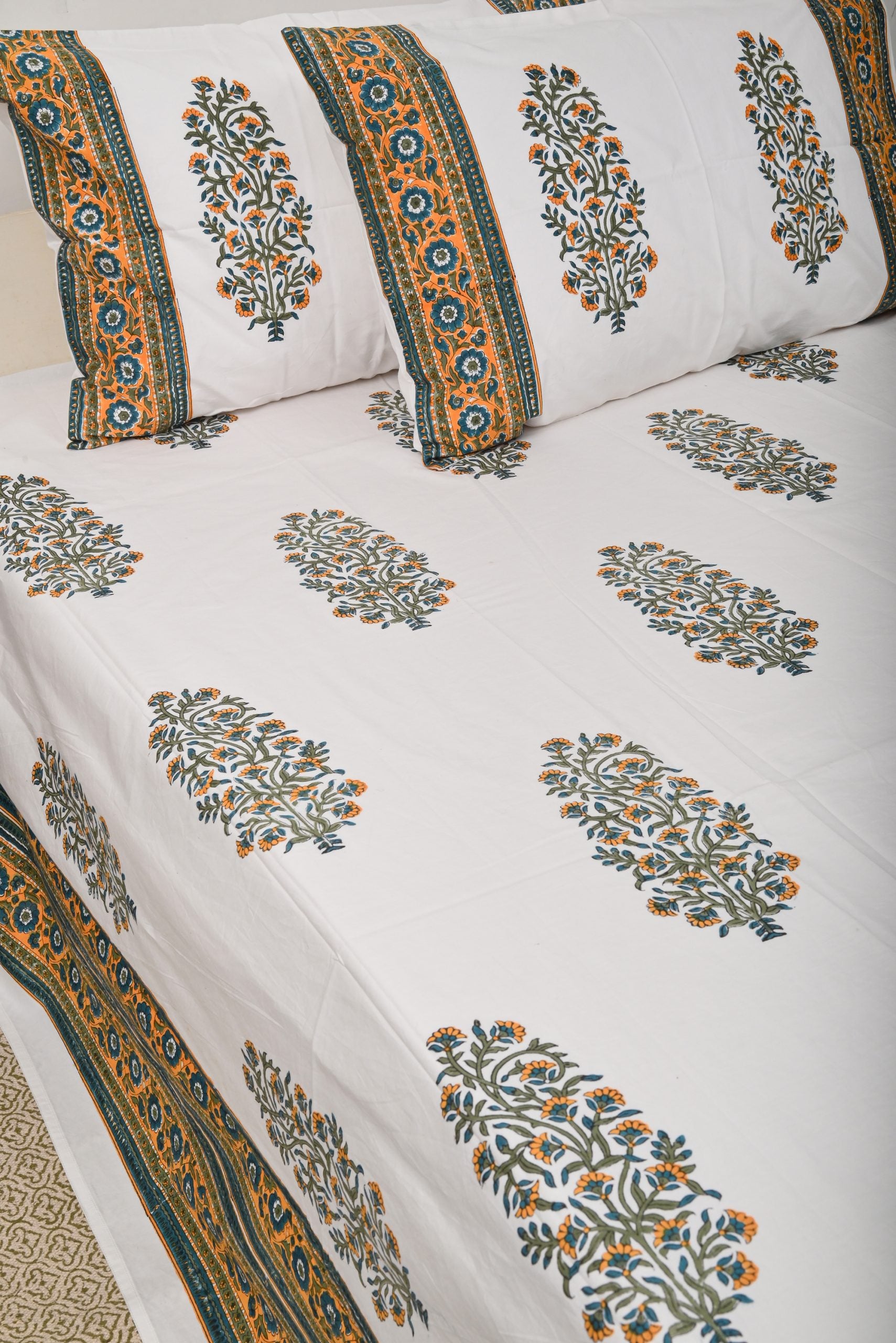 Floral patterned bedspread with decorative pillows on a white background