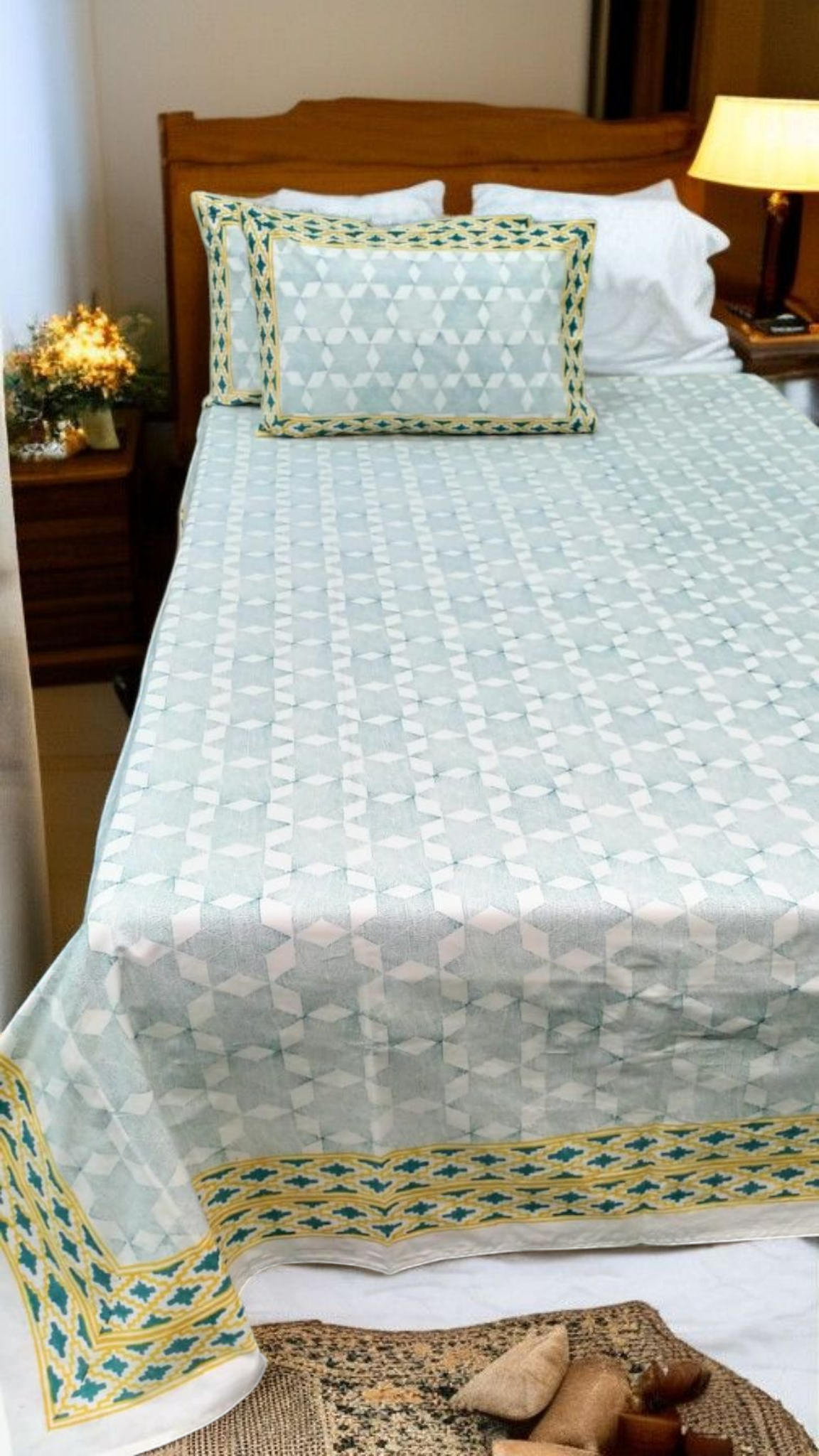 Bed with a light green quilt and matching pillows in a bedroom setting.