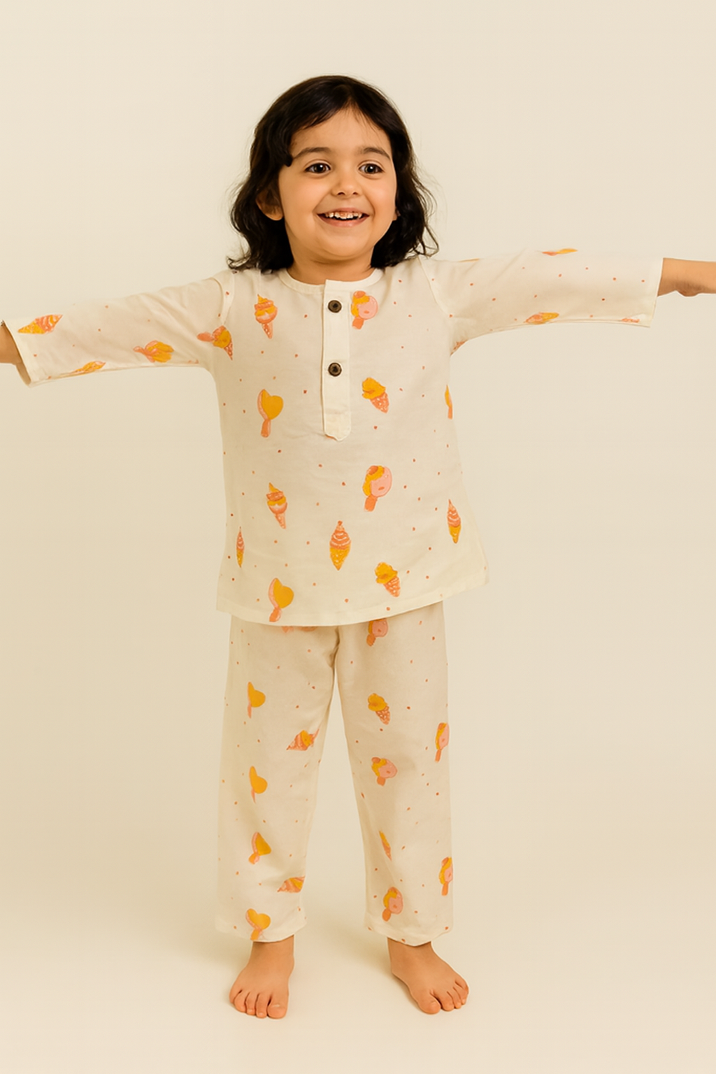 Child wearing a cream-colored pajama set with ice cream pattern on a plain background