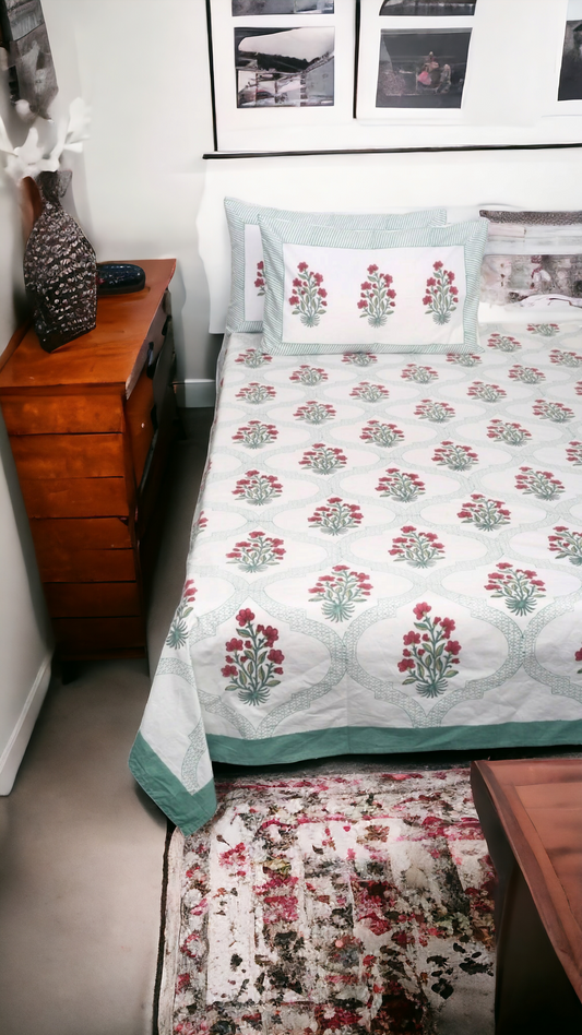 Bedroom with floral bedspread on a bed, wooden dresser, and framed pictures on the wall.